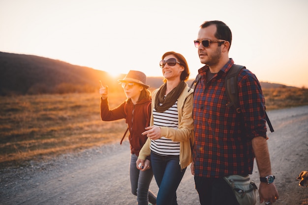 Happy family hiking on a dirt road during sunset