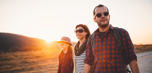 Happy family hiking on a dirt road during sunset