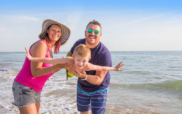 Happy family holding boy hands on beach