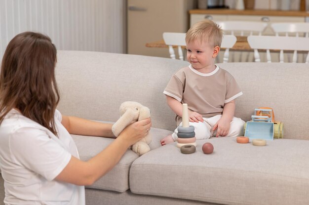 Happy family at home mother and baby boy playing with toys in couch at home indoors little toddler