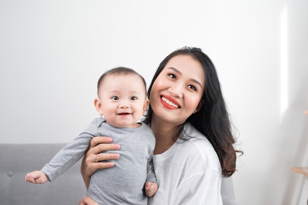 Happy family at home. Mother holding baby daughter in living room in cozy weekend morning