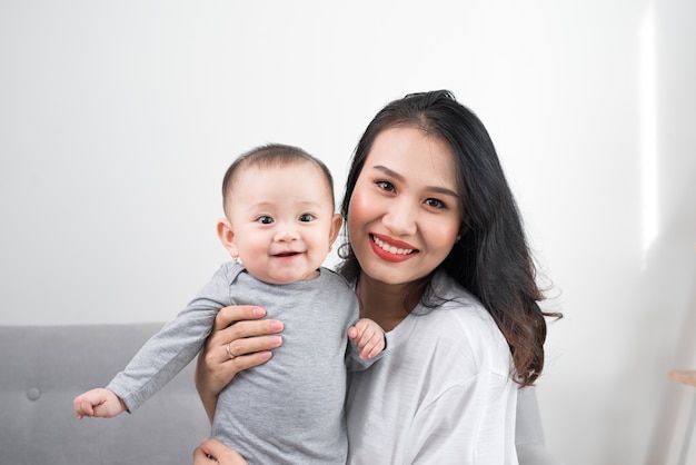 Happy family at home. Mother holding baby daughter in living room in cozy weekend morning