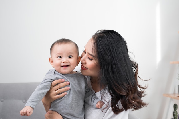 Happy family at home. Mother holding baby daughter in living room in cozy weekend morning