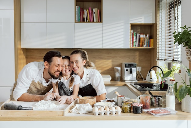 Happy family hugging in aprons before cooking baking homemade delicious pizza