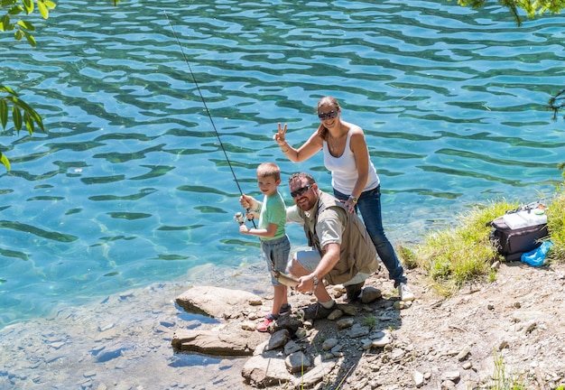 happy family is fishing together in the river on mountain