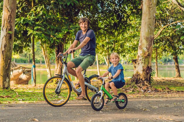 Happy family is riding bikes outdoors and smiling. Father on a bike and son on a balancebike