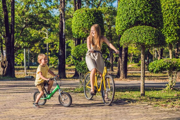 Happy family is riding bikes outdoors and smiling. Mom on a bike and son on a balancebike.