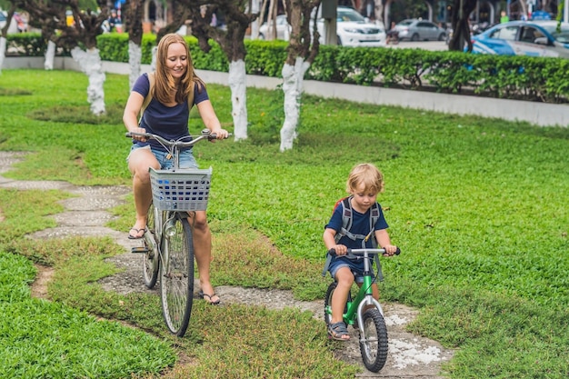 Happy family is riding bikes outdoors and smiling. Mom on a bike and son on a balancebike.