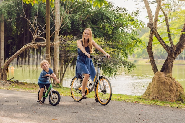 Happy family is riding bikes outdoors and smiling. Mom on a bike and son on a balancebike