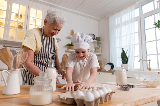 Happy family in kitchen grandmother and granddaughter child cook in kitchen together grandma teachin