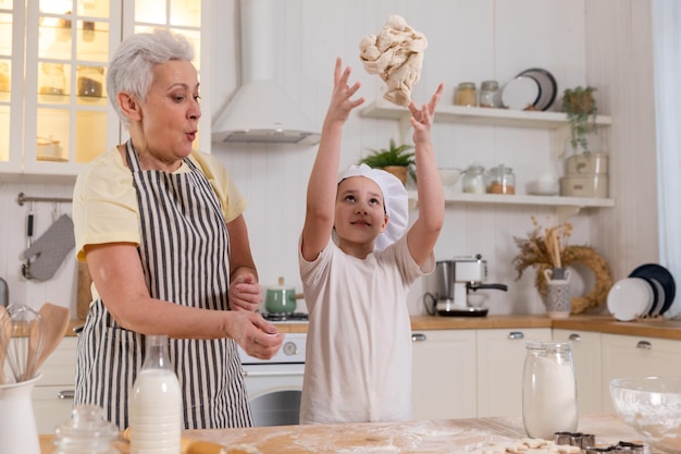 Happy family in kitchen grandmother and granddaughter child cook in kitchen together grandma teachin