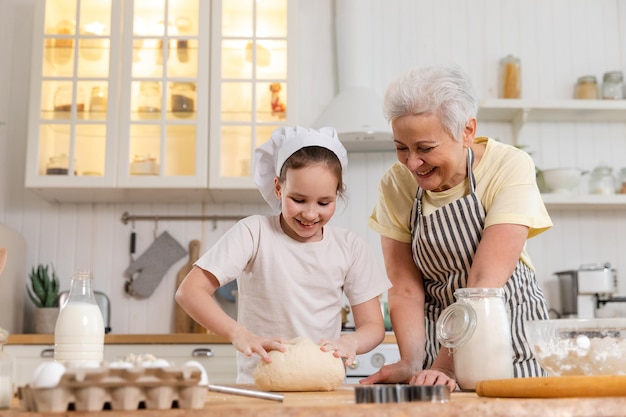 Happy family in kitchen grandmother and granddaughter child cook in kitchen together grandma teachin