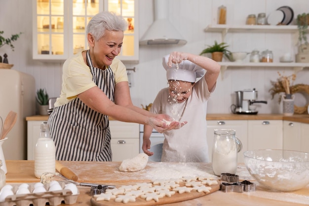 Happy family in kitchen grandmother and granddaughter child cook in kitchen together grandma teachin