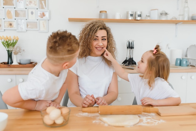 Happy family in the kitchen. mother and children preparing the dough, bake cookies