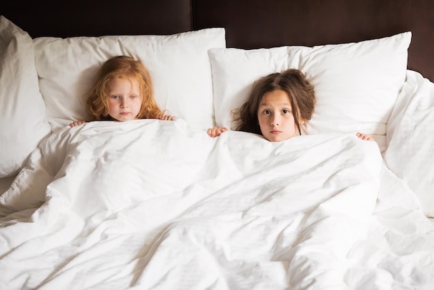 Happy family lying under blanket in bed at home