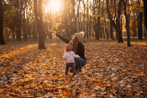 Happy family mom and baby girl playing outdoors in fall park little girl and her mother in the