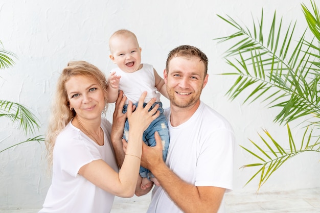 Photo happy family, mom, dad and baby son smiling on a white background and hugging