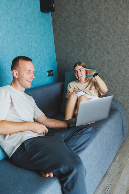 Happy family mom dad and cute baby son having fun using laptop at home Young parents and funny toddler child boy spending lifestyle time at computer sitting on couch