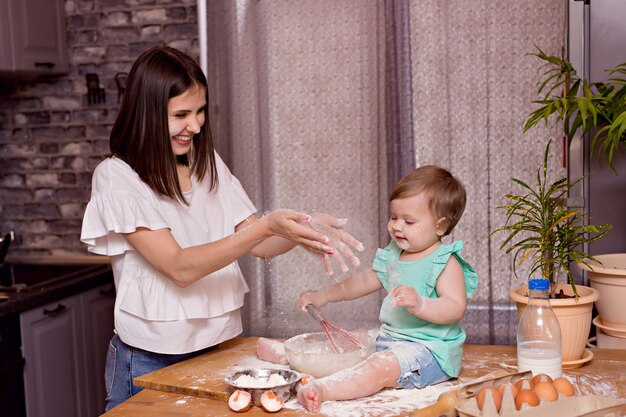 Happy family, mom, daughter play and cook in the kitchen, knead the dough and bake cookies