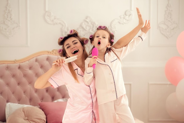 Happy family mom and daughter spending time together at home singing in a comb having fun