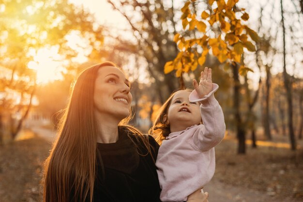 Happy family mom and toddler baby girl playing outdoors in fall park little girl and her mother in