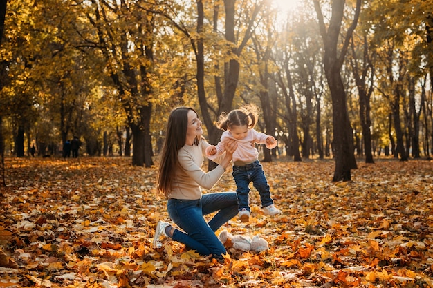 Happy family mom and toddler baby girl playing outdoors in fall park little girl and her mother in