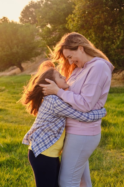 Happy family mother and child daughter in nature Park in summer on green grass