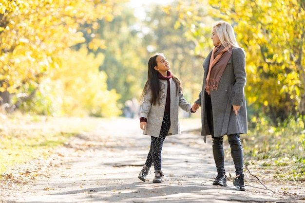 happy family: mother and child little daughter play on autumn walk in nature outdoors.