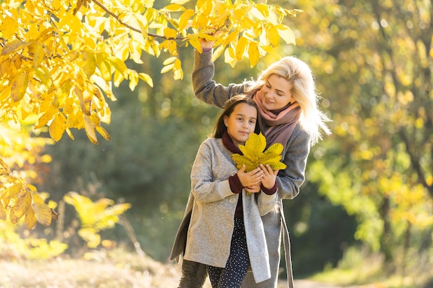 happy family: mother and child little daughter play on autumn walk in nature outdoors.