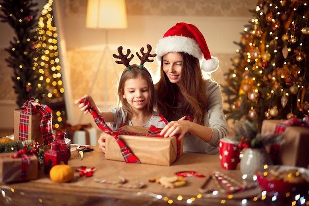 A happy family mother and child pack Christmas gifts