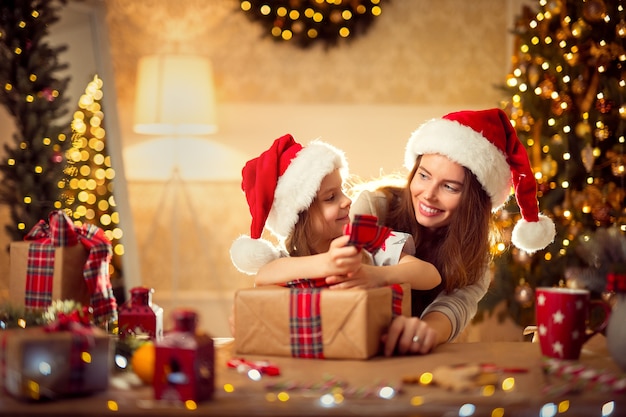 A happy family mother and child pack Christmas gifts