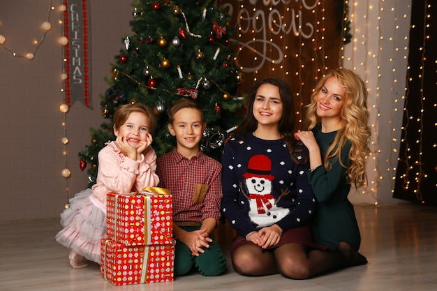 Happy family mother and children on Christmas at the Christmas tree with gifts.