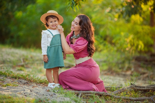 a happy family. mother and daughter have fun on a walk in the park. beautiful mom in a pink dress and daughter in a green sundress