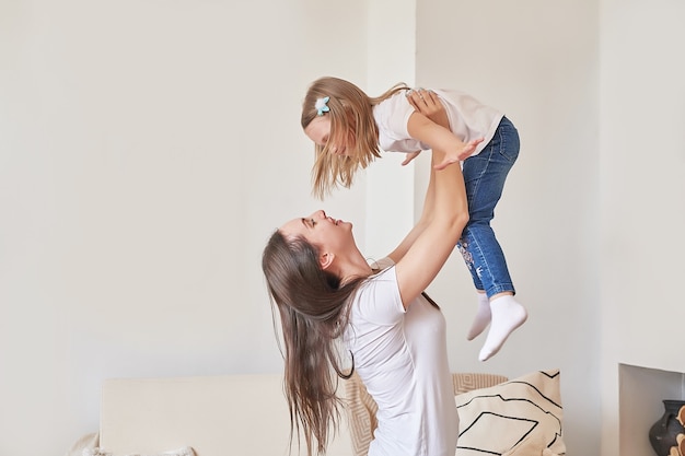 Happy family. Mother and daughter at home. Young woman and girl. Mothers and childrens day. Good morning and love concept. Light home interior.