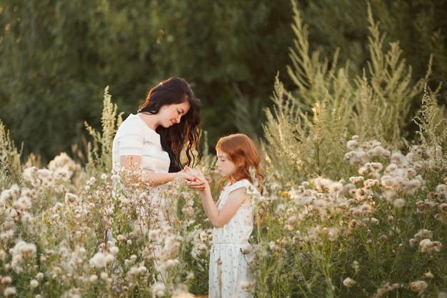 Happy family mother and daughter spend summer time together in green field