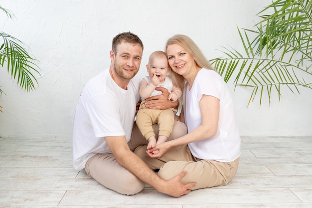 Happy family mother father and baby hug and smile young parents at home