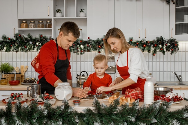 Happy family mother father and little son are concentrated on cooking Christmas bisquits