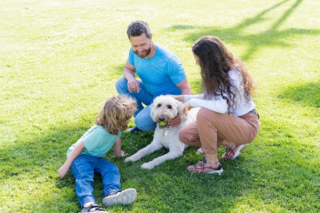 Happy family of mother father and son playing with dog in park on green grass, family.