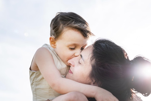 Happy family of mother and infant child walking on wheat field hugging and kissing