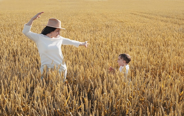 Happy family of mother and infant child walking on wheat field