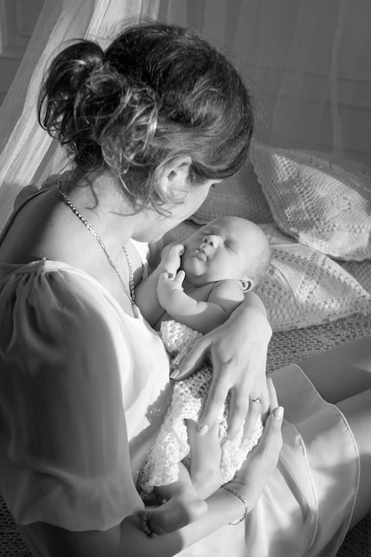 Happy family mother playing and hug with newborn baby in bed