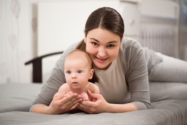 Happy family. Mother playing with her baby in the bedroom.