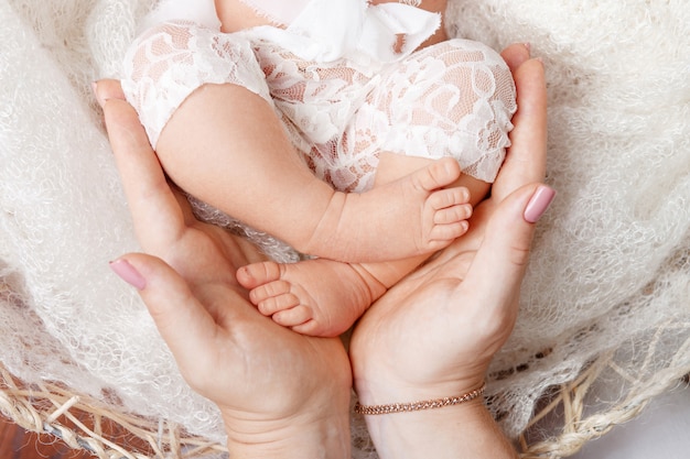 Happy family . Newborn baby feet in mother hands in white