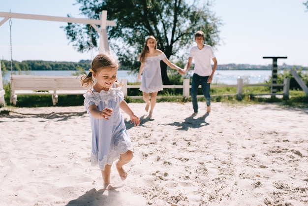 Happy family outdoors spending time together. Father, mother and daughter are having fun and running on a beach