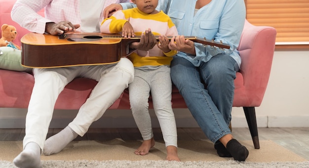 Happy family playing guitar together on the couch in living room at home