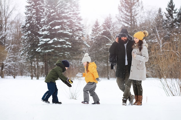 Happy family playing and laughing in winter outdoors in the snow. City park winter day.