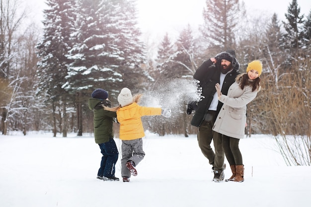 Happy family playing and laughing in winter outdoors in the snow. City park winter day.