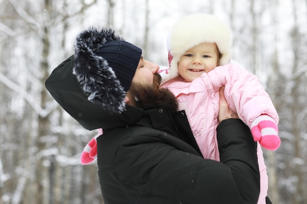 Happy family playing and laughing in winter outdoors in the snow. City park winter day.