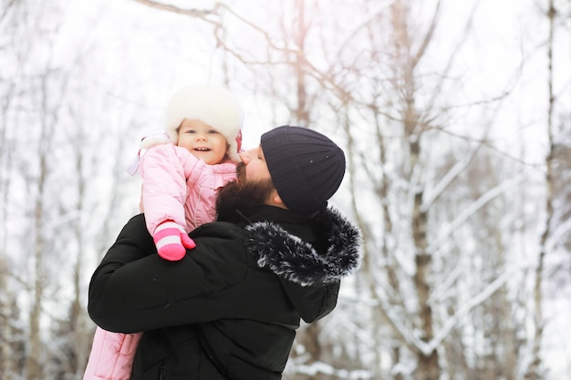 Happy family playing and laughing in winter outdoors in the snow. City park winter day.