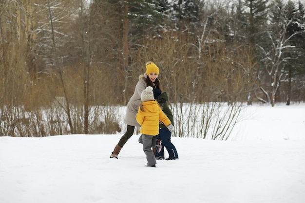 Happy family playing and laughing in winter outdoors in the snow. City park winter day.